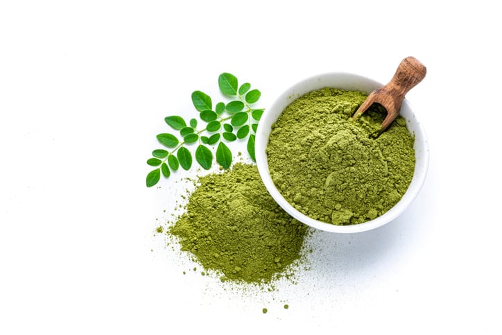 A photo showing matcha tea powder and moringa leaves.