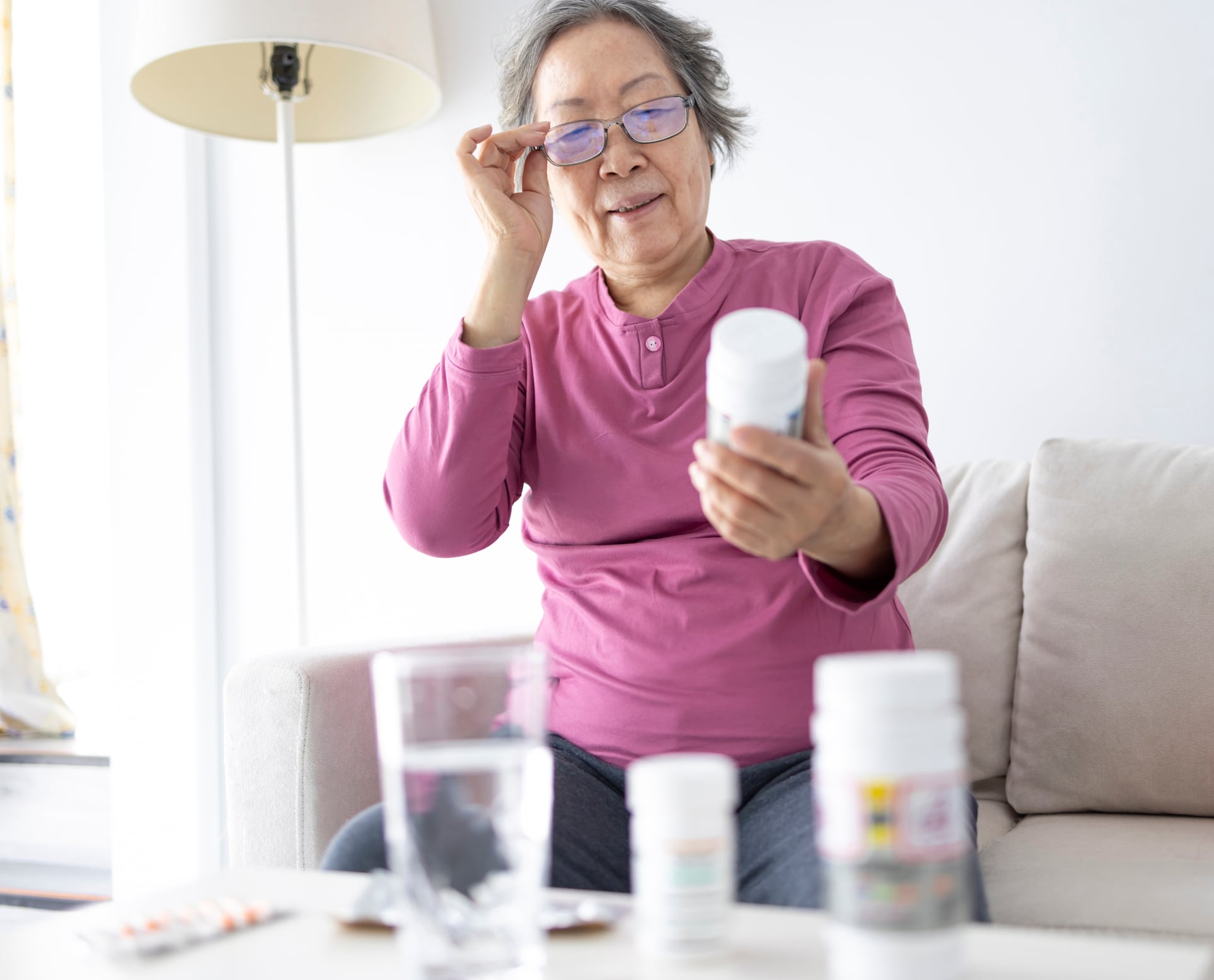 A senior woman reading the contents on a bottle of health supplements.