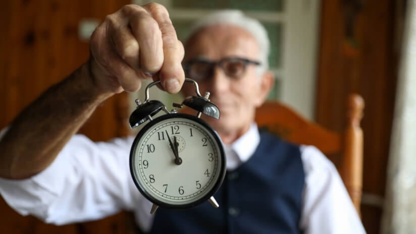 Older man holding a clock