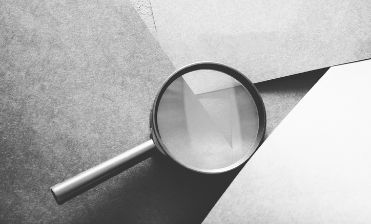 A magnifying glass placed on top of grey layered paper. ©Getty Images 